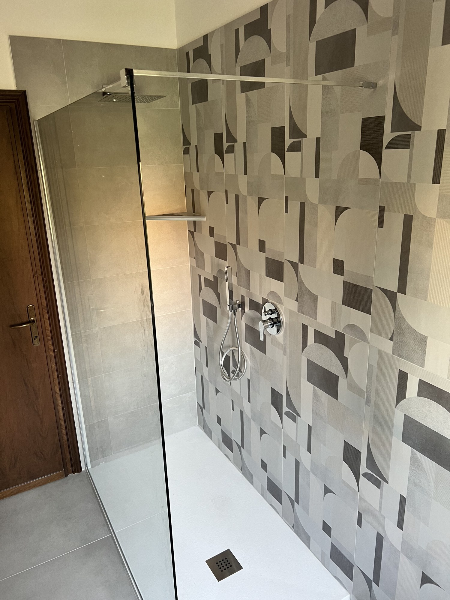 Bagno grigio con doccia walk-in e piastrelle geometriche