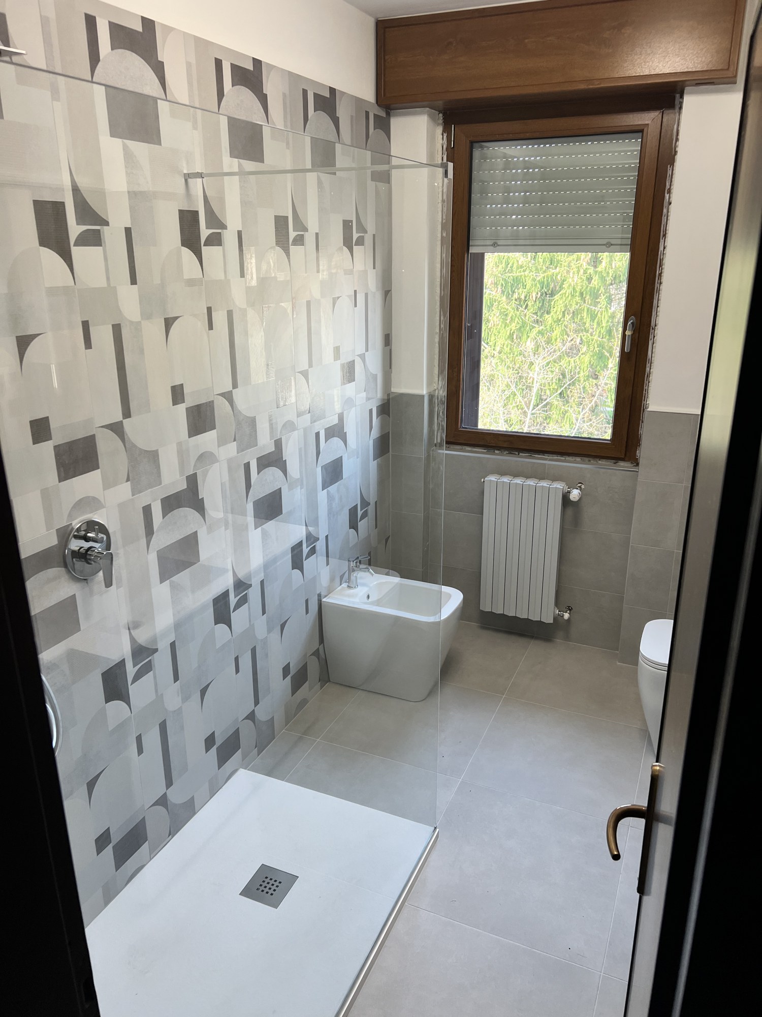 Bagno grigio con doccia walk-in e piastrelle geometriche
