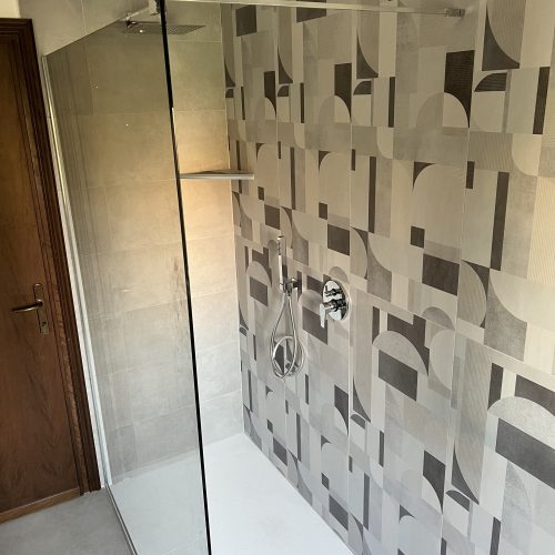 Bagno grigio con doccia walk-in e piastrelle geometriche